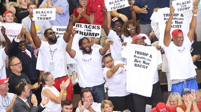 photo of "Michael The Black Man" and his cult entourage holding up signs that read "Blacks For Trump" at a Trump Rally